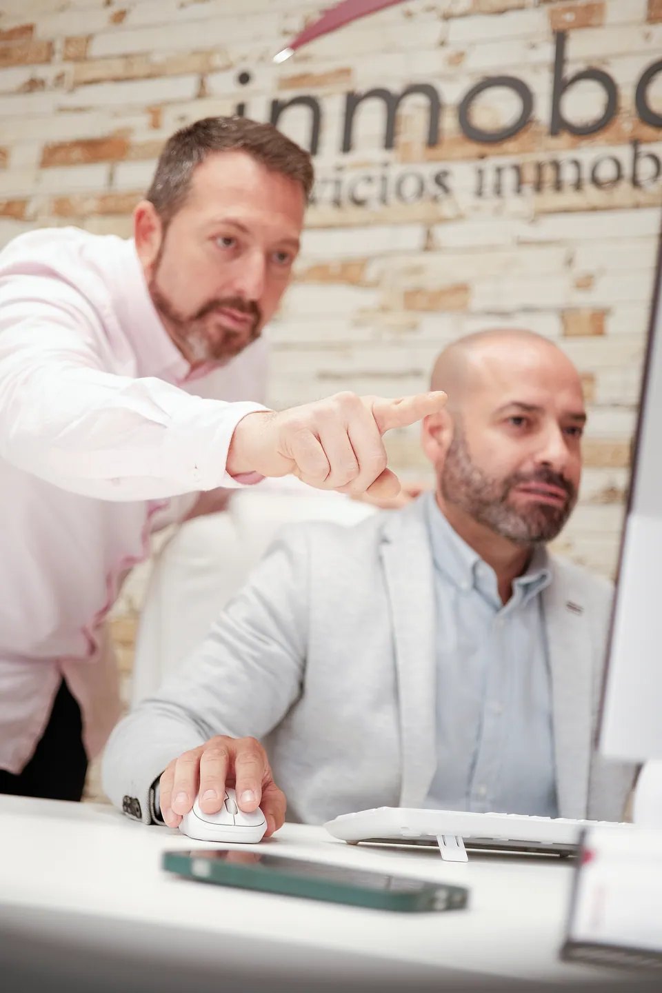 Profesionales de Inmobalia revisando información en una pantalla.