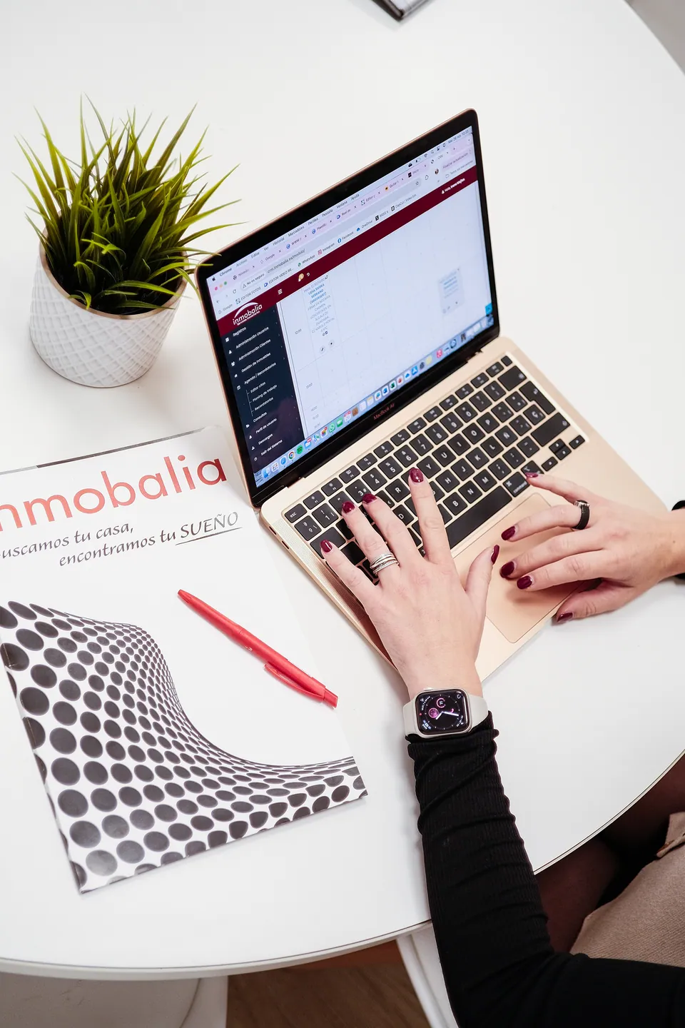 Puesto de trabajo con portátil y documentación de Inmobalia.
